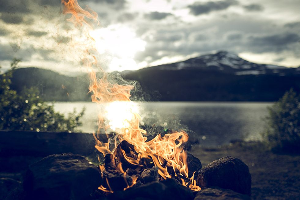 Campfire by a lake with mountains