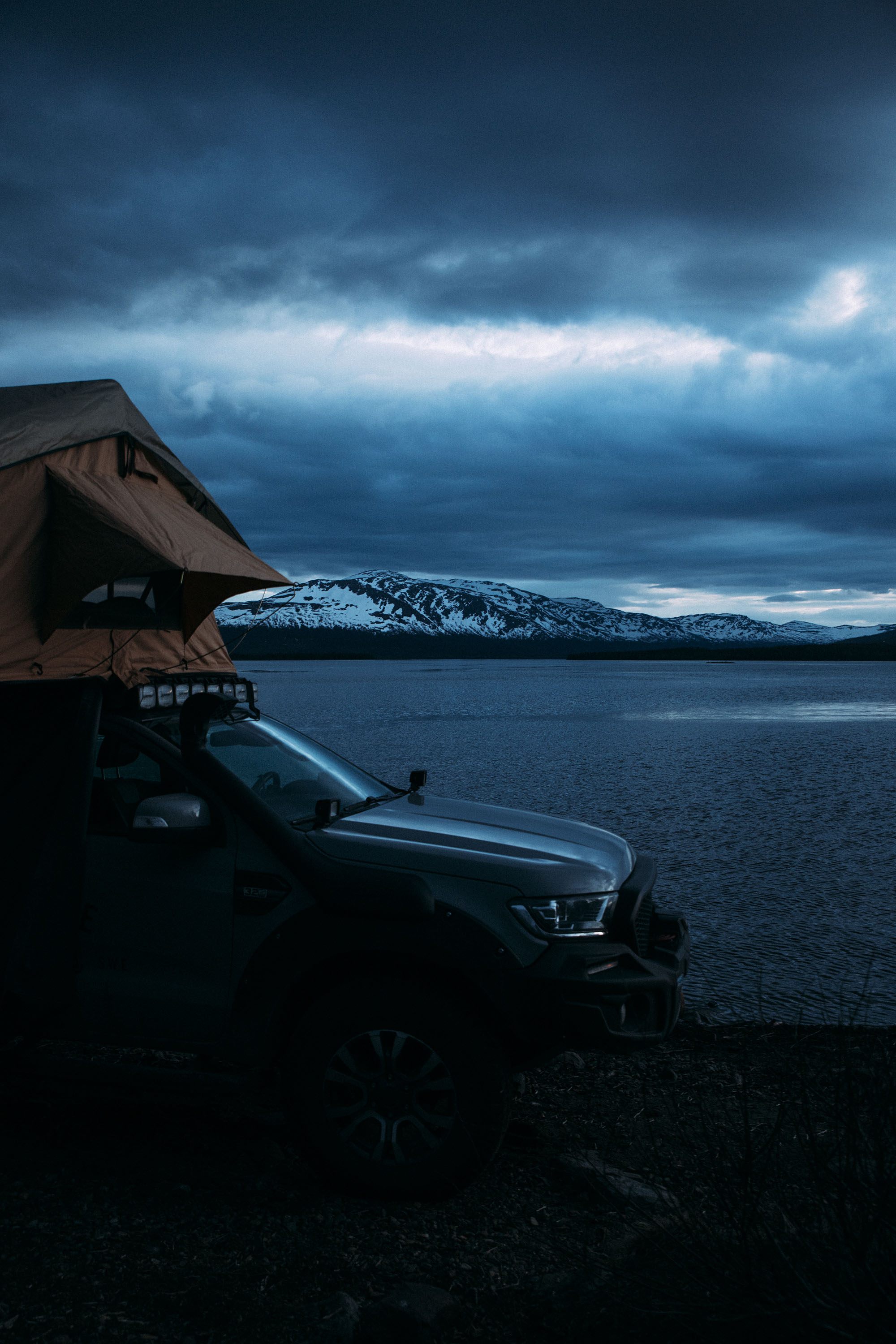 Vehicle with rooftop tent beside a northern lake